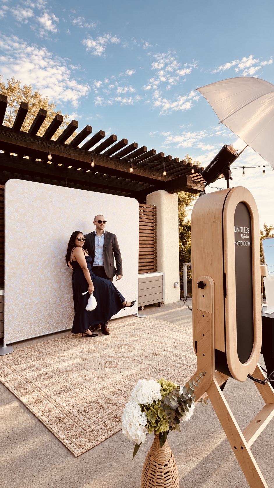 Couple posing beside the mirror photobooth at an outdoor celebration